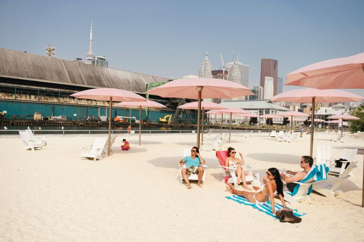 Beachgoers soak up the sun while the skyscrapers glisten in the background Image C/O Canadian Tourism Commission